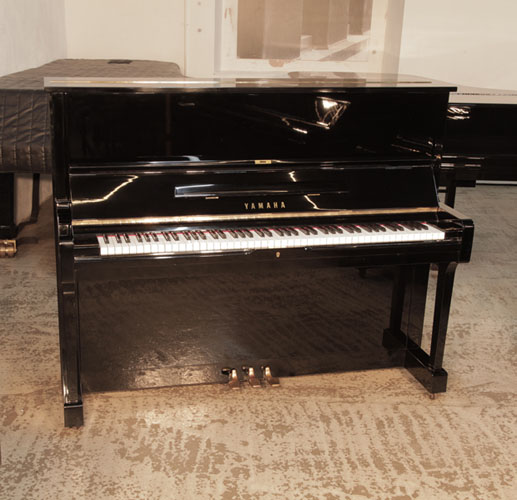  Reconditioned,  1975, Yamaha U1 upright piano in black gloss with brass fittings. Piano has an eighty-eight note keyboard and three pedals. 