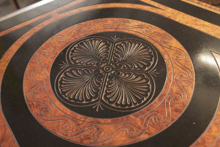 Piano lid circular motif in black and walnut bordered with spiralling rope and four symmetrical anthemions in low relief  