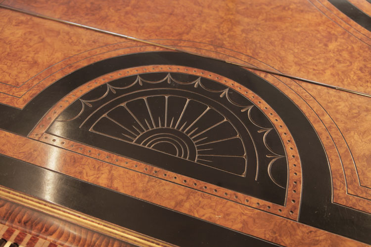 Piano lid semi-circular motif in black and walnut of a sun bordered with stylised swags and palm leaves in low relief 
