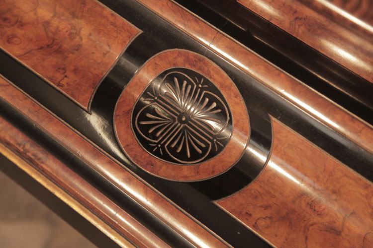 The piano fall repeats smaller versions of the decorative carvings seen on the lid. A circular motif in black and walnut contains stylised palm leaves