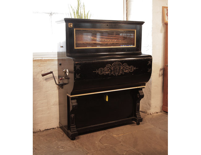Frederick Gray & Co Barrell Piano. Cabinet features etched decoration on fall. There is a slot to take old pennies for operation. The cabinet features a glass front panel which allows the action to be visible. .