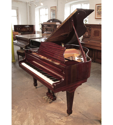A 1986, Kawai KG-1D baby grand piano with a mahogany case and spade legs. Piano has an eighty-eight note keyboard and a three-pedal lyre.