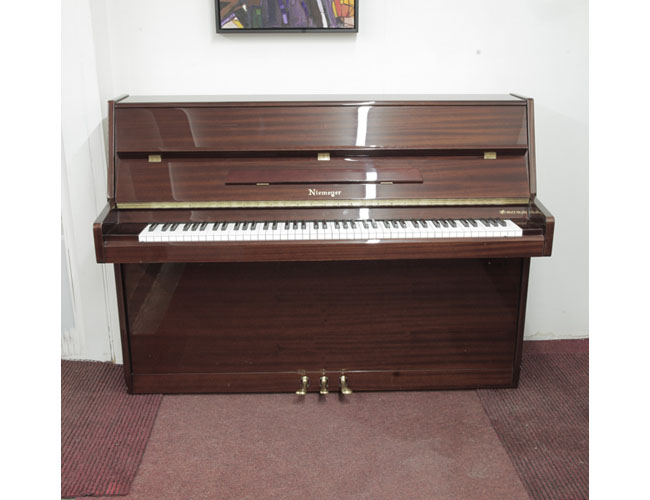 Pre-owned, Niemeyer upright piano with a mahogany gloss case. Piano has an eighty-eight note keyboard and three pedals. 