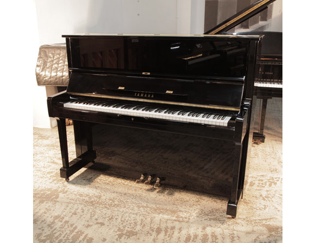 Reconditioned,  1977, Yamaha U1 upright piano in black gloss with brass fittings. Piano has an eighty-eight note keyboard and three pedals