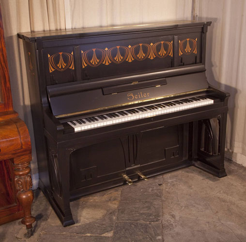 A 1906, Seiler upright piano with a Jugenstil, black satin case. Piano has an eighty-five note keyboard and two pedals.